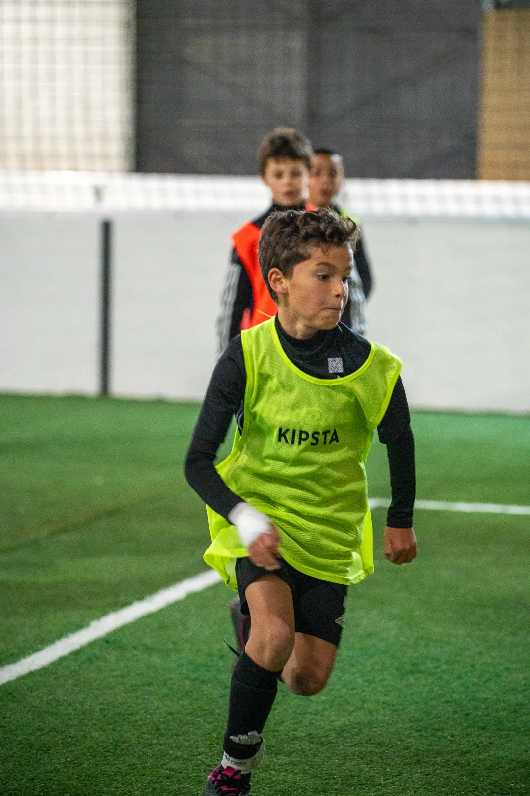 Enfant courant balle au pied sur le terrain